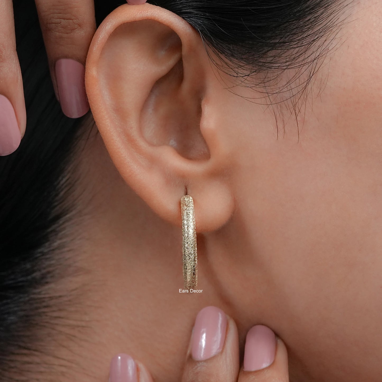 14k gold matte finish hoop earrings on womanโs ear