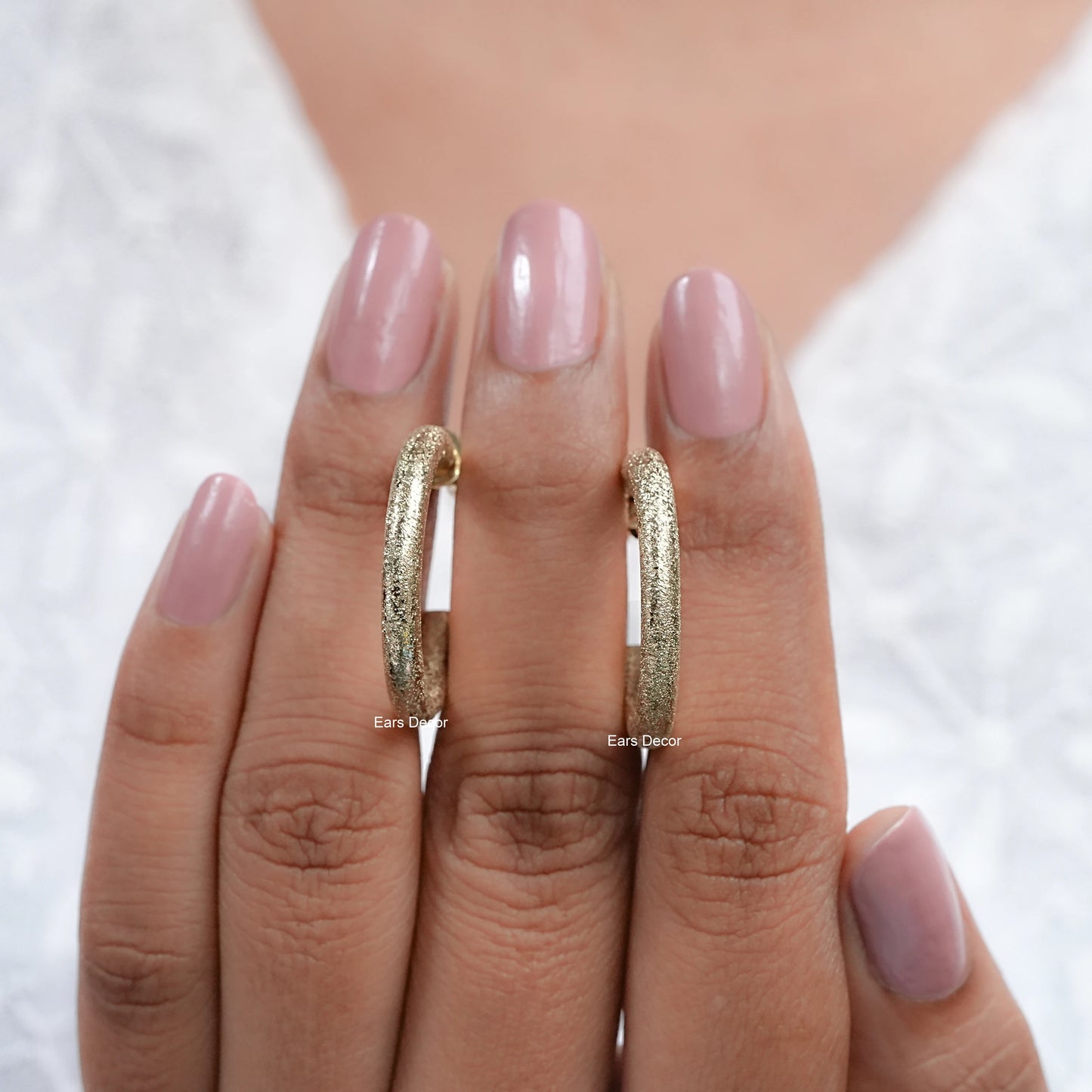 gold matte finish hoop earrings display a detailed view on the fingers