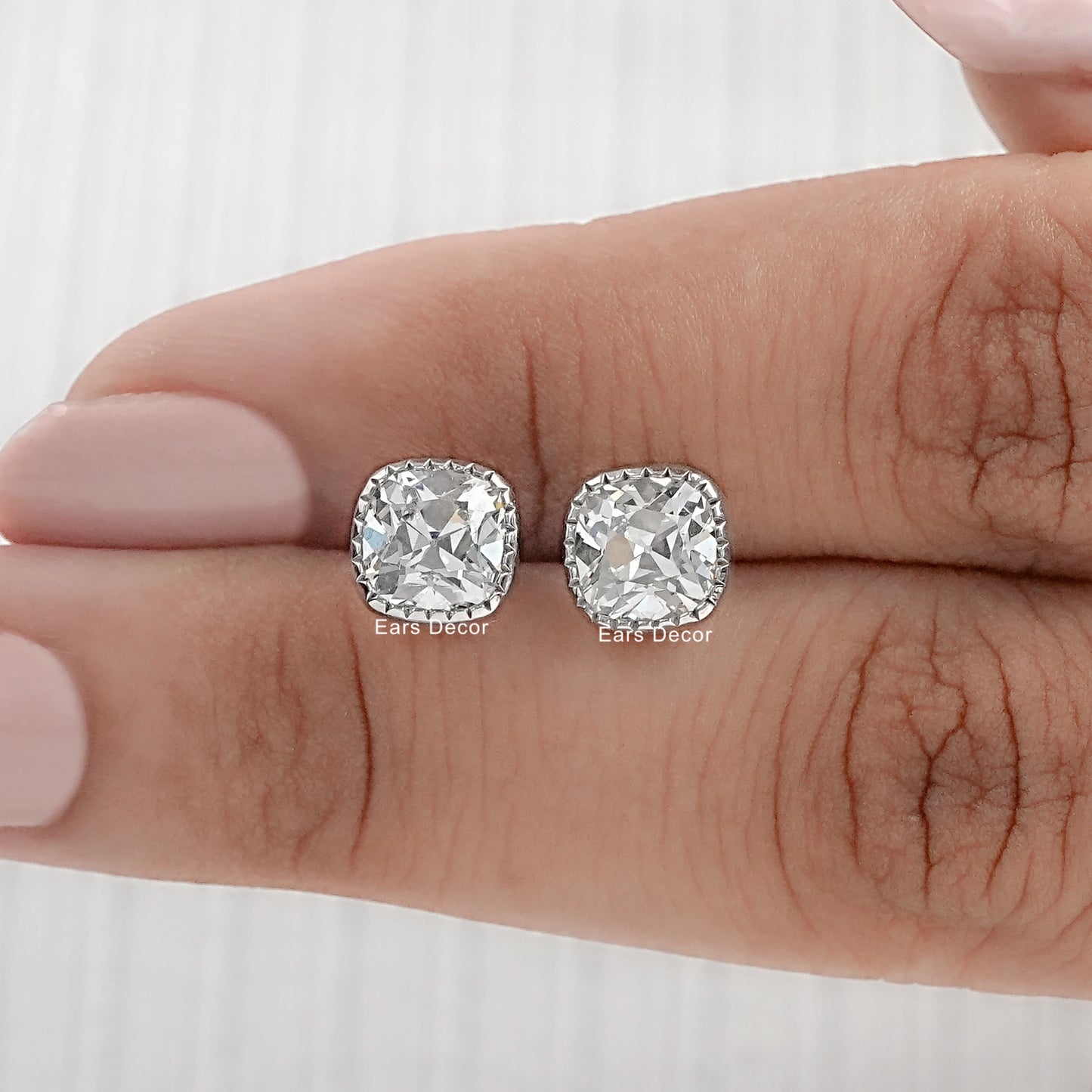 Cushion old mine milgrain earrings resting flat on palm showing full milgrain bezel detail