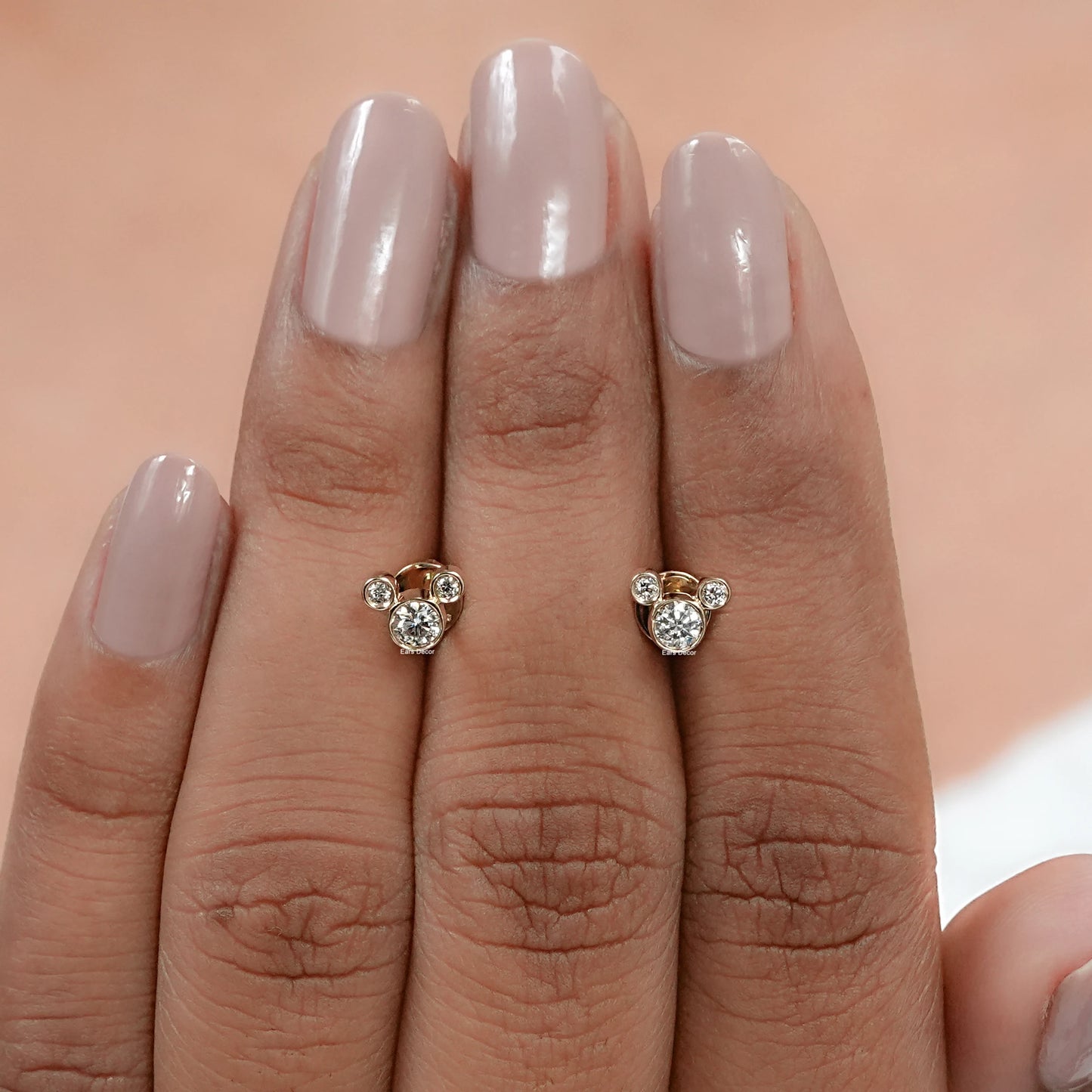 pair of mickey mouse round diamond stud earrings displayed on fingers