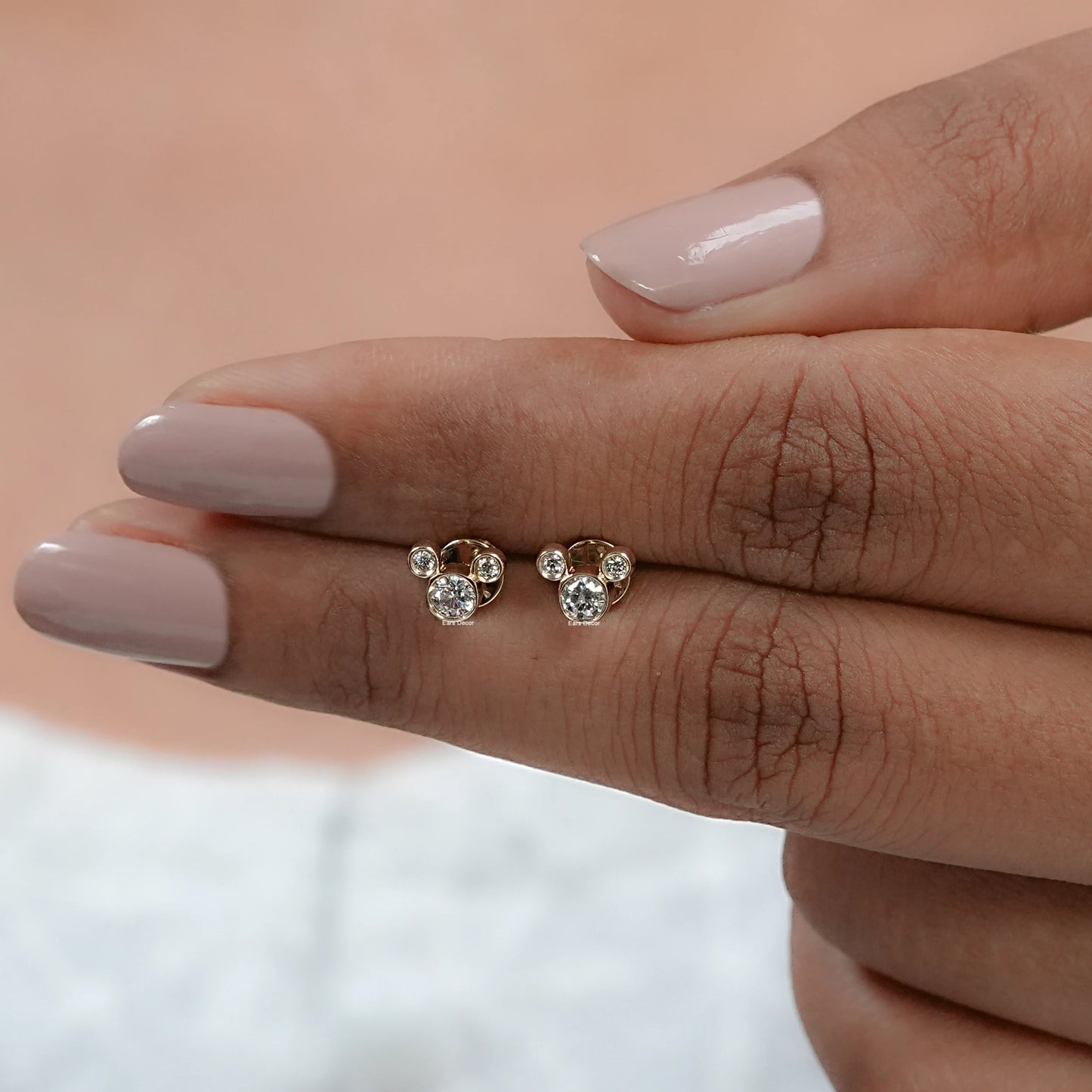 front view of mickey mouse diamond studs held closely with fingers