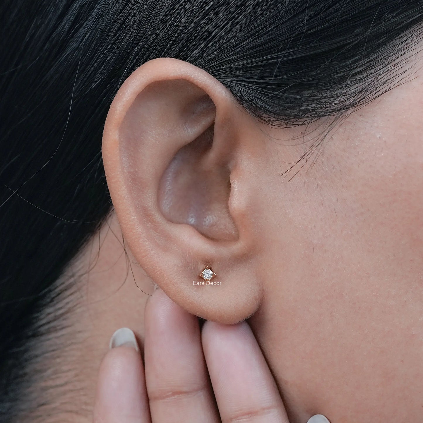 a round natural diamond stud worn in the earlobe by a female