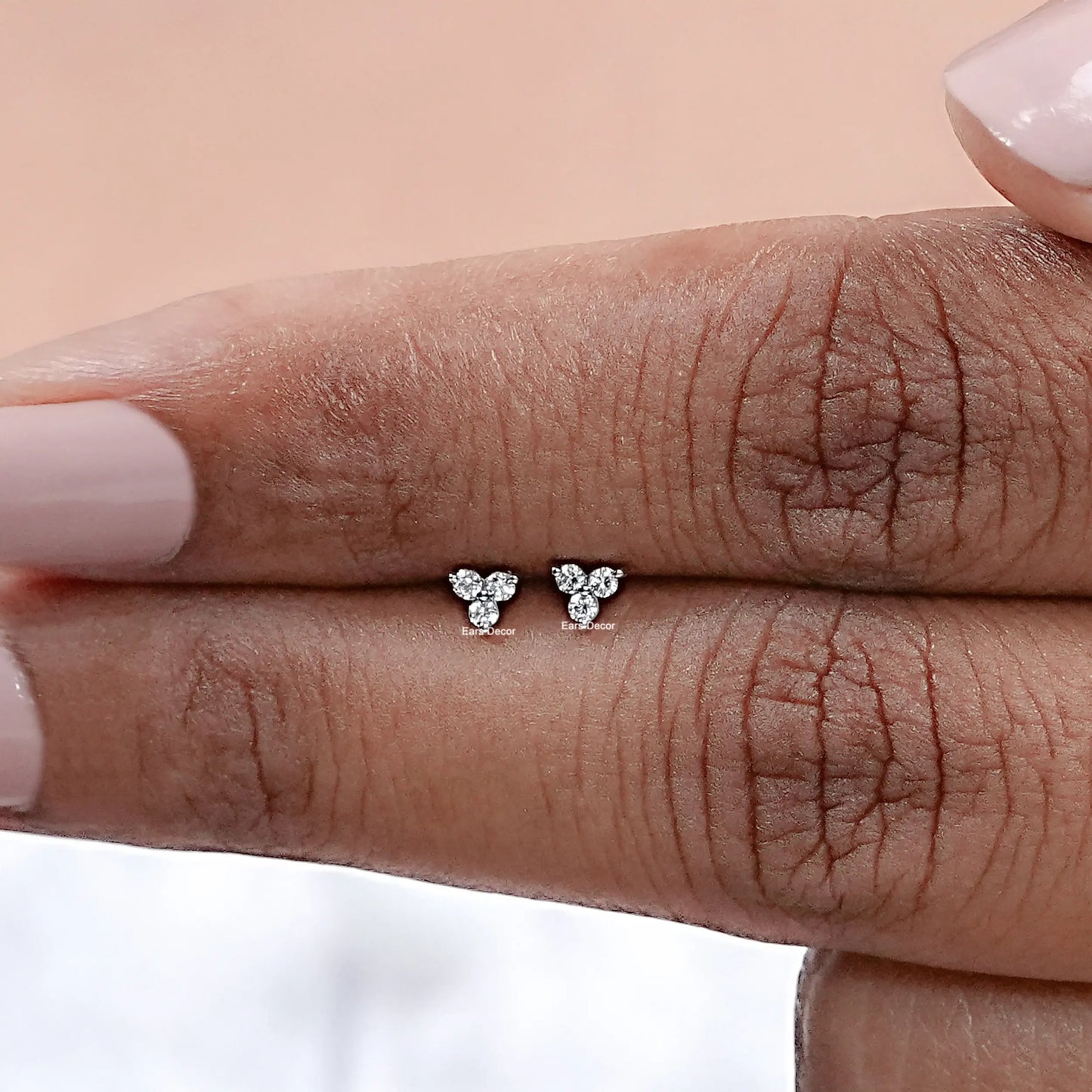 tiny three stone natural diamond stud close up on fingers