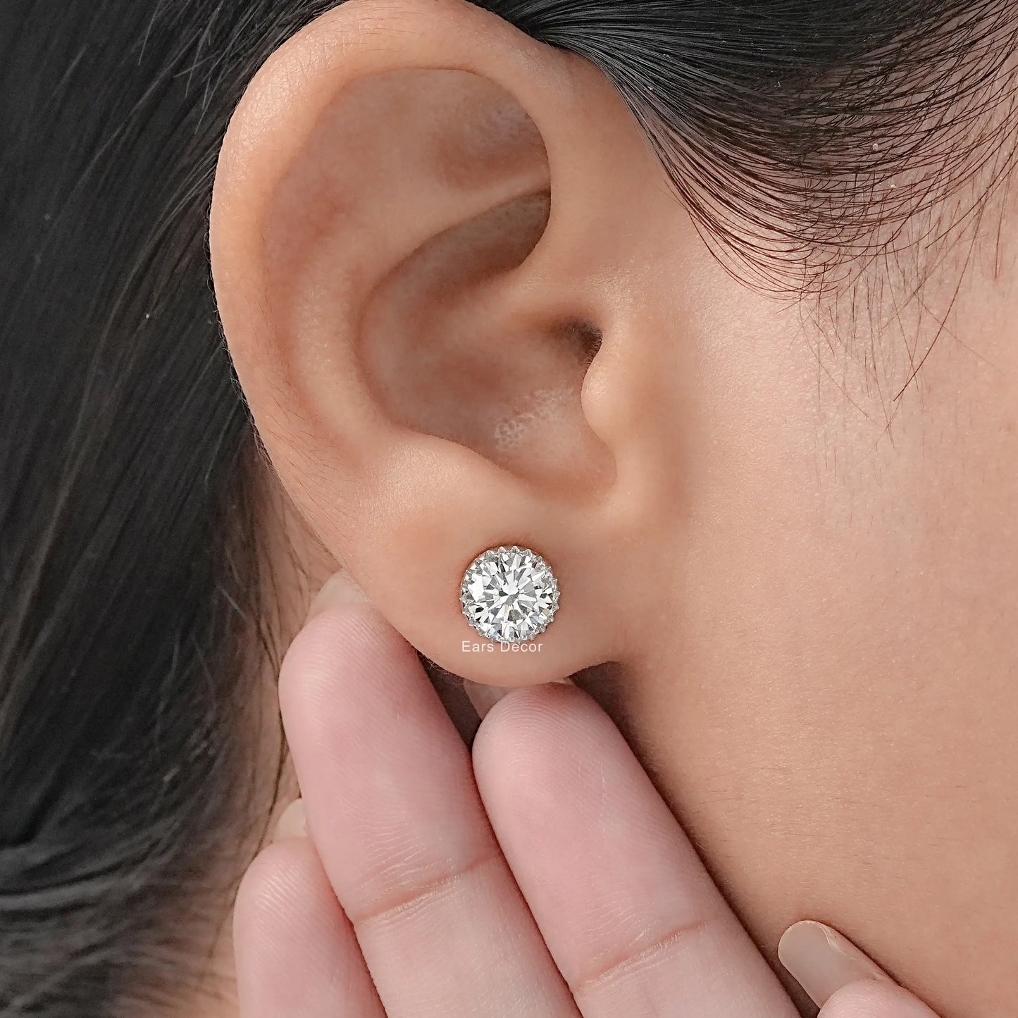 Screw back moissanite stud earrings secure fit white gold worn on model ear hand pose close-up