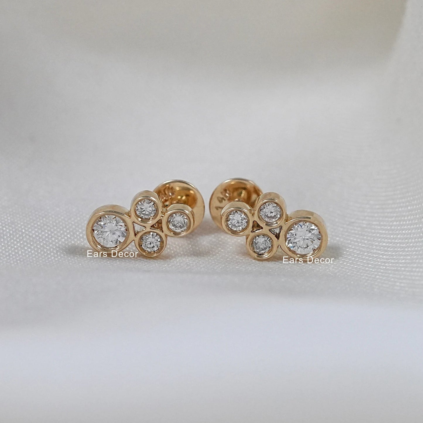 Round shape natural minimalist earrings pair on white cloth, three bezel set round stones in yellow gold