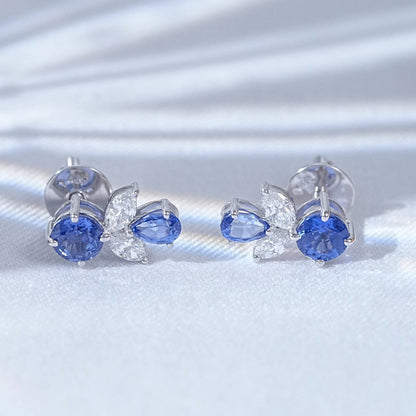 Blue sapphire butterfly stud earrings pair white gold white satin flat lay close-up view