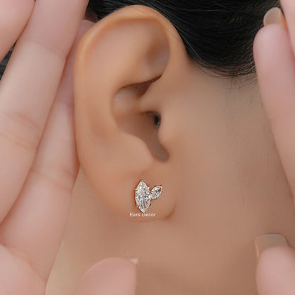 Minimal Toi et Moi diamond earrings with marquise cut stones worn on a model ear framed by hands.