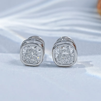 Cushion shape bezel diamond studs pair white gold luxury satin flatlay jewelry display
