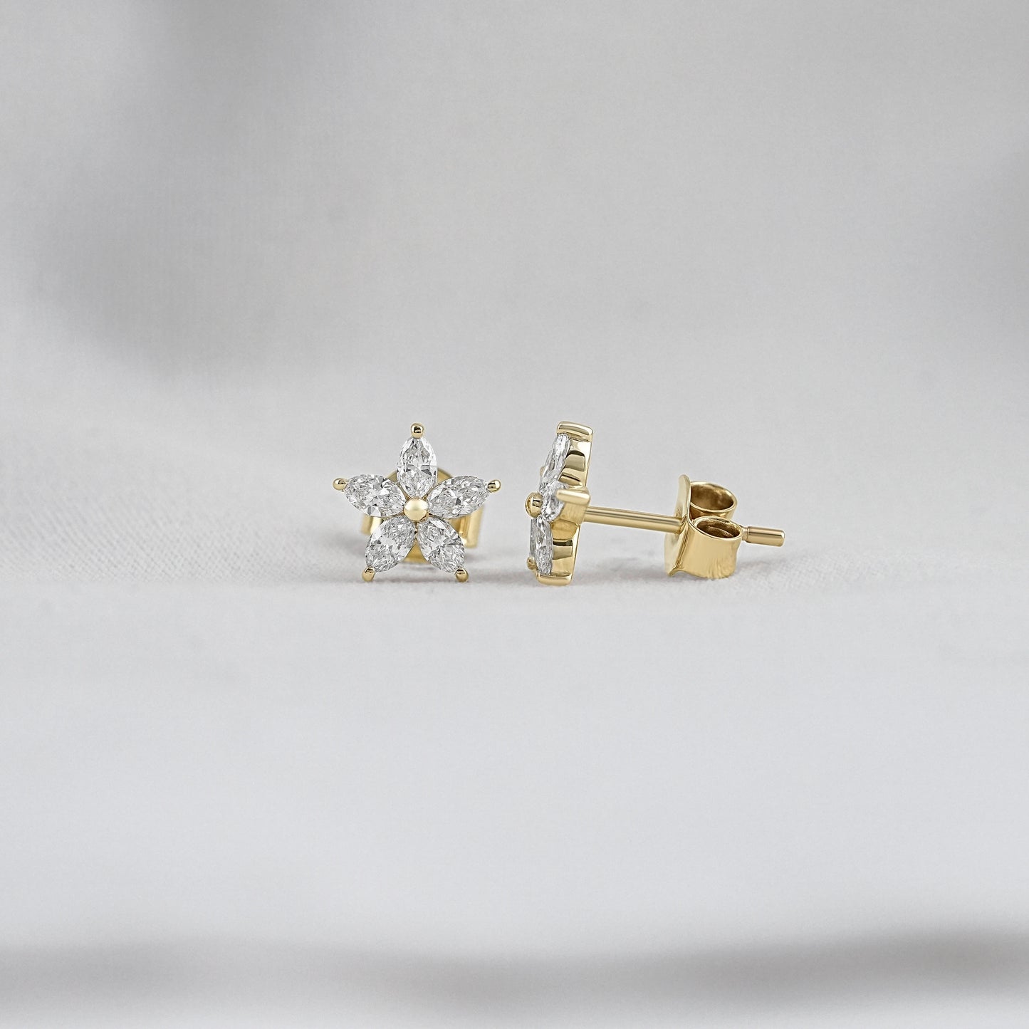 Marquise diamond flower stud earrings featuring five brilliant petals around a central gold bead.