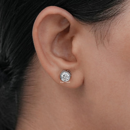 Old European round cut lab diamond bezel set stud earrings shown on a model's ear.
