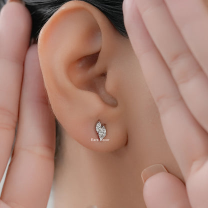 Small dainty toi et moi diamond studs cartilage or lobe worn on model ear close-up dark hair both hands framing face warm skin