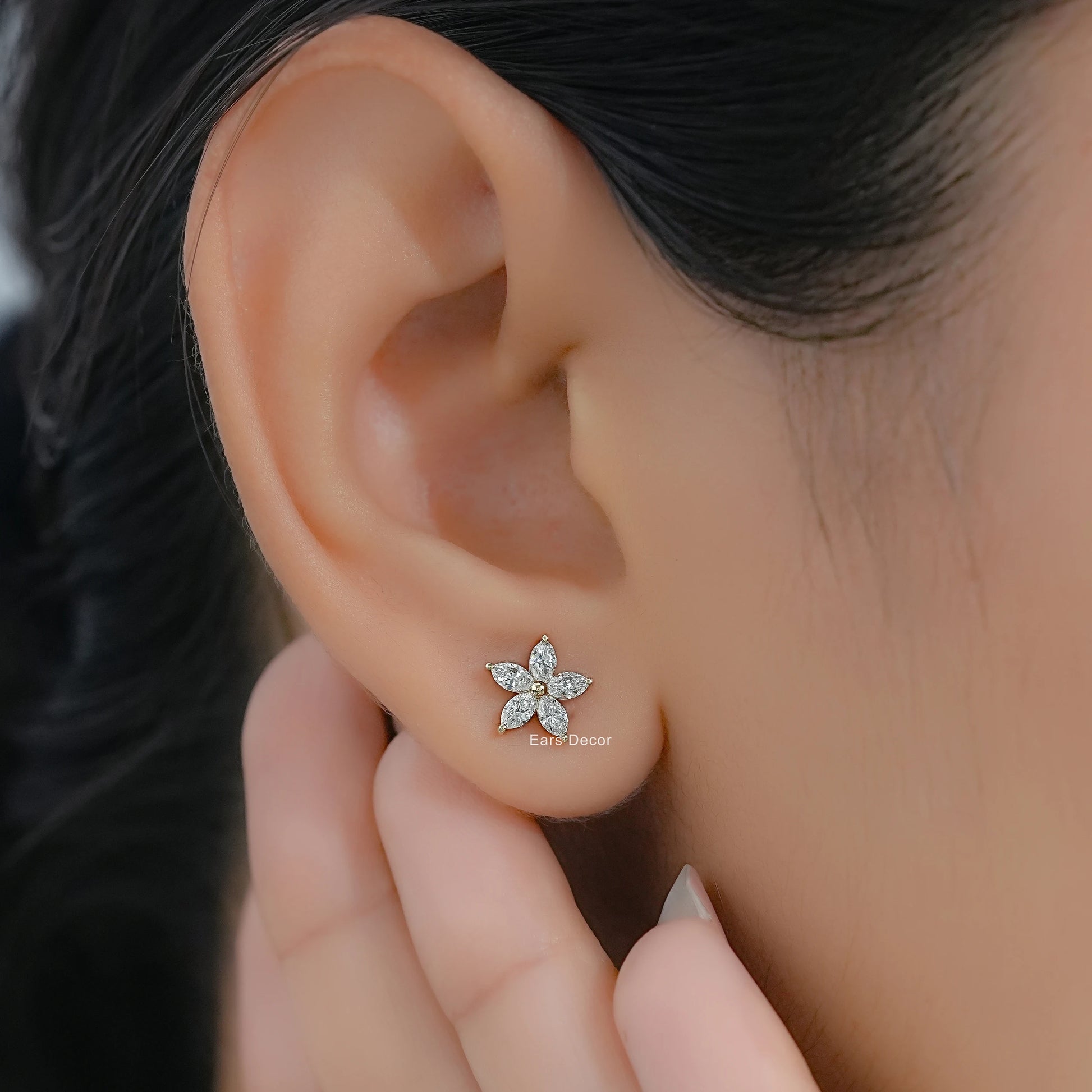 Small floral cluster diamond stud earrings in solid yellow gold worn on a model with a clean profile view.