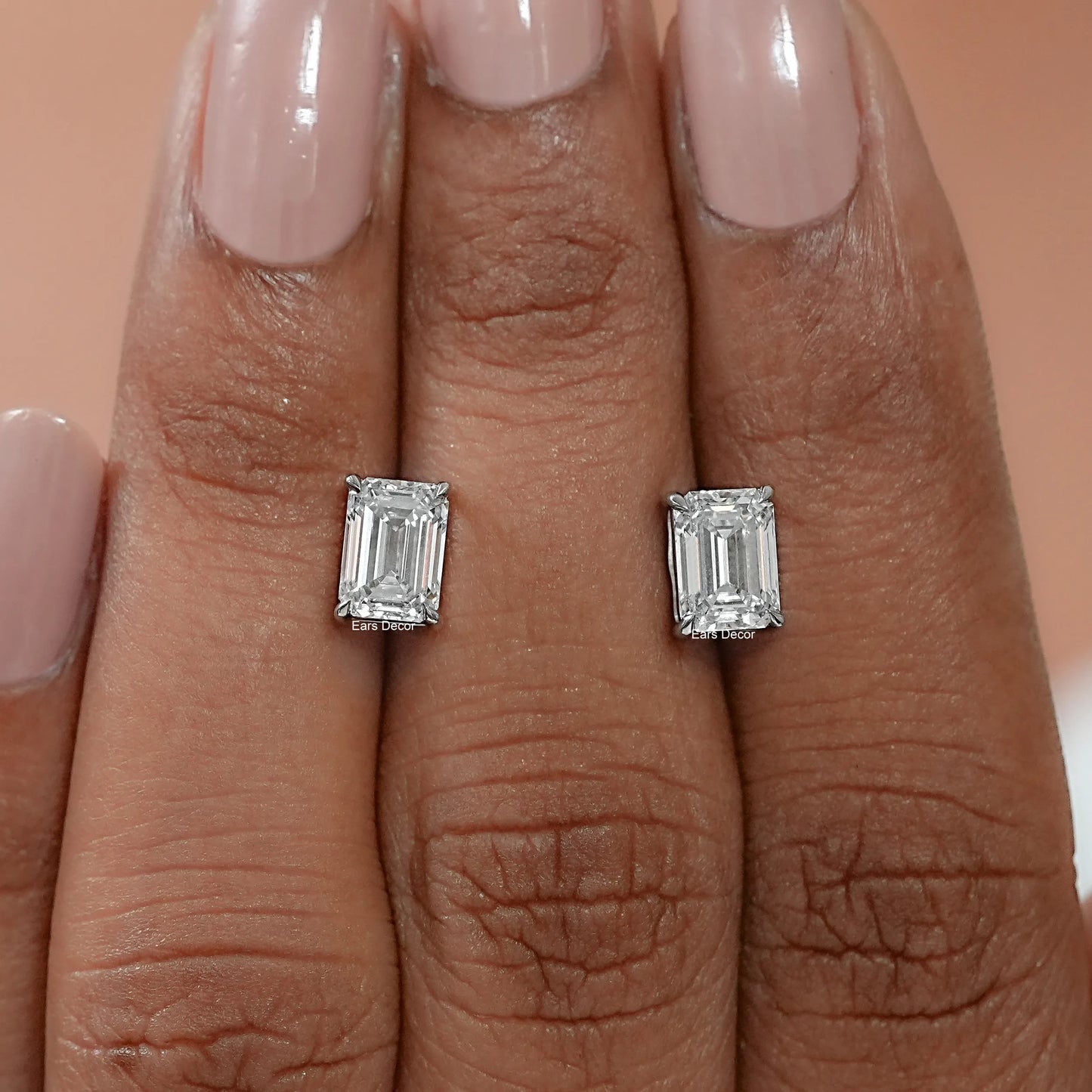 Coordinated emerald cut stud earrings displayed on the palm, expressing reassuring weight, handcrafted quality, and a brilliantly polished hallmarked finish.