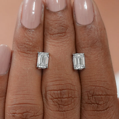 Coordinated emerald cut stud earrings displayed on the palm, expressing reassuring weight, handcrafted quality, and a brilliantly polished hallmarked finish.