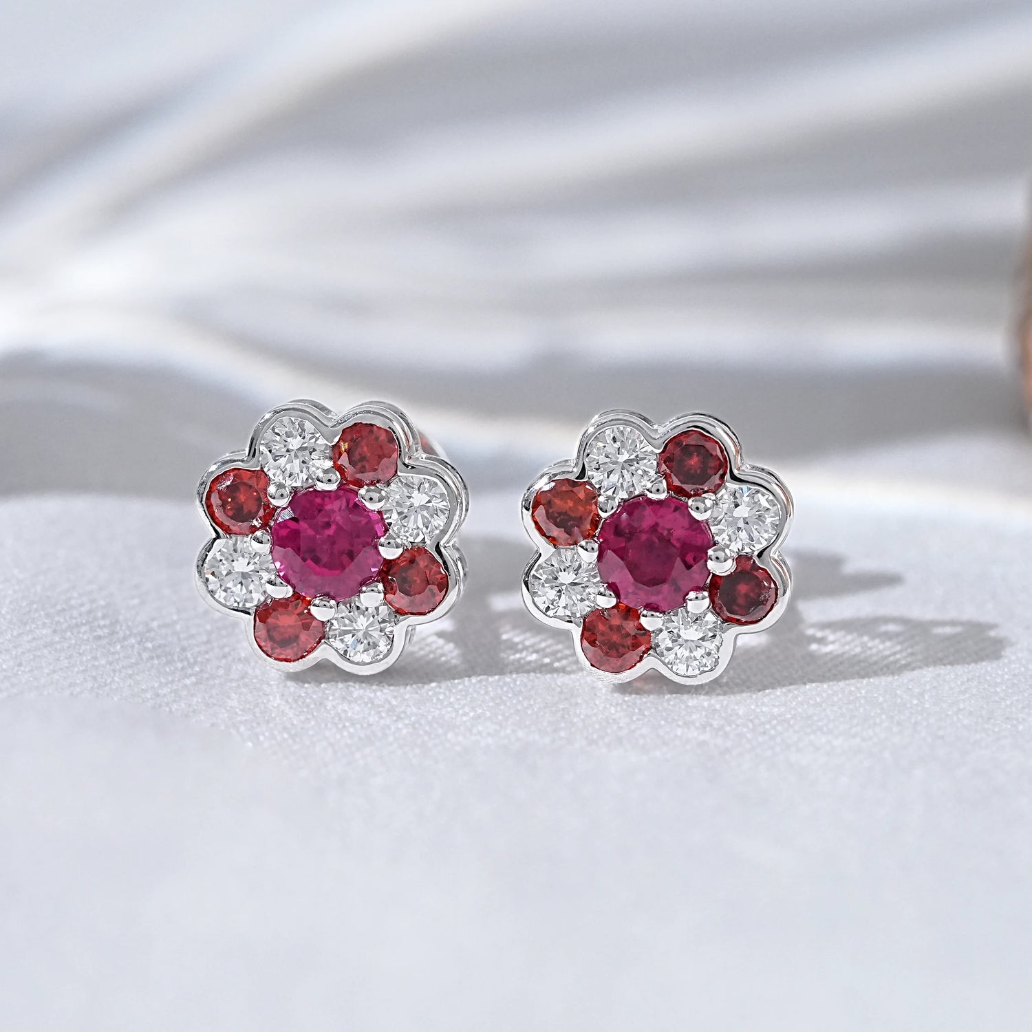 Flower ruby stud earrings for women pair white gold white satin flat lay close-up view