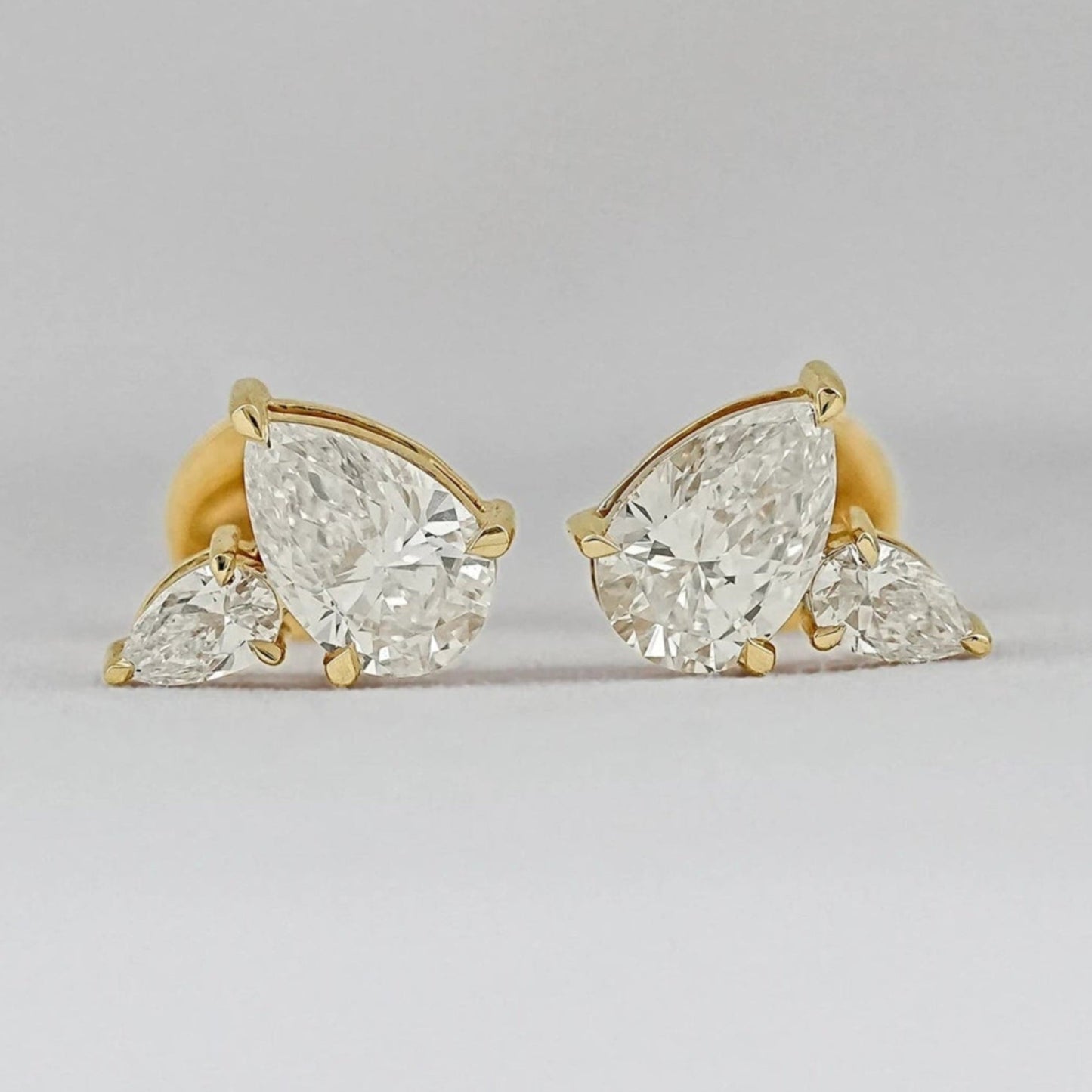Pear shaped diamond cluster stud earrings 14k yellow gold large and small pear cut stones matching pair close-up product shot