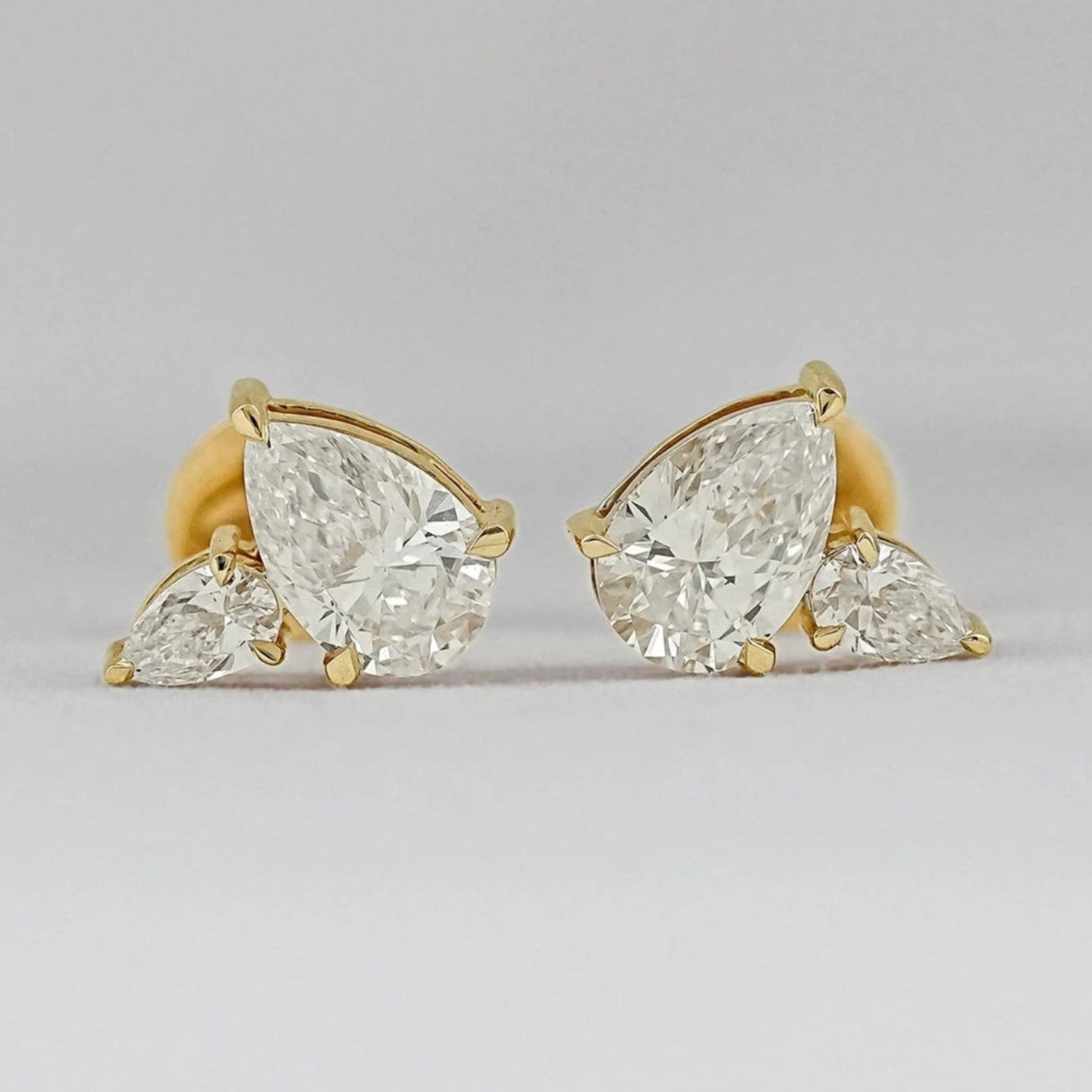 Pear shaped diamond cluster stud earrings 14k yellow gold large and small pear cut stones matching pair close-up product shot