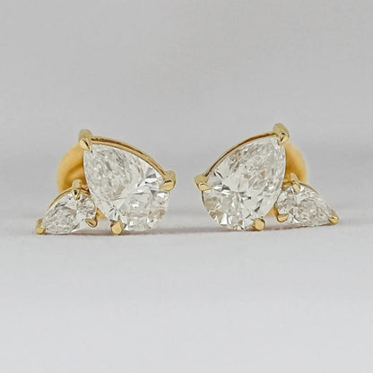 Pear shaped diamond cluster stud earrings 14k yellow gold large and small pear cut stones matching pair close-up product shot