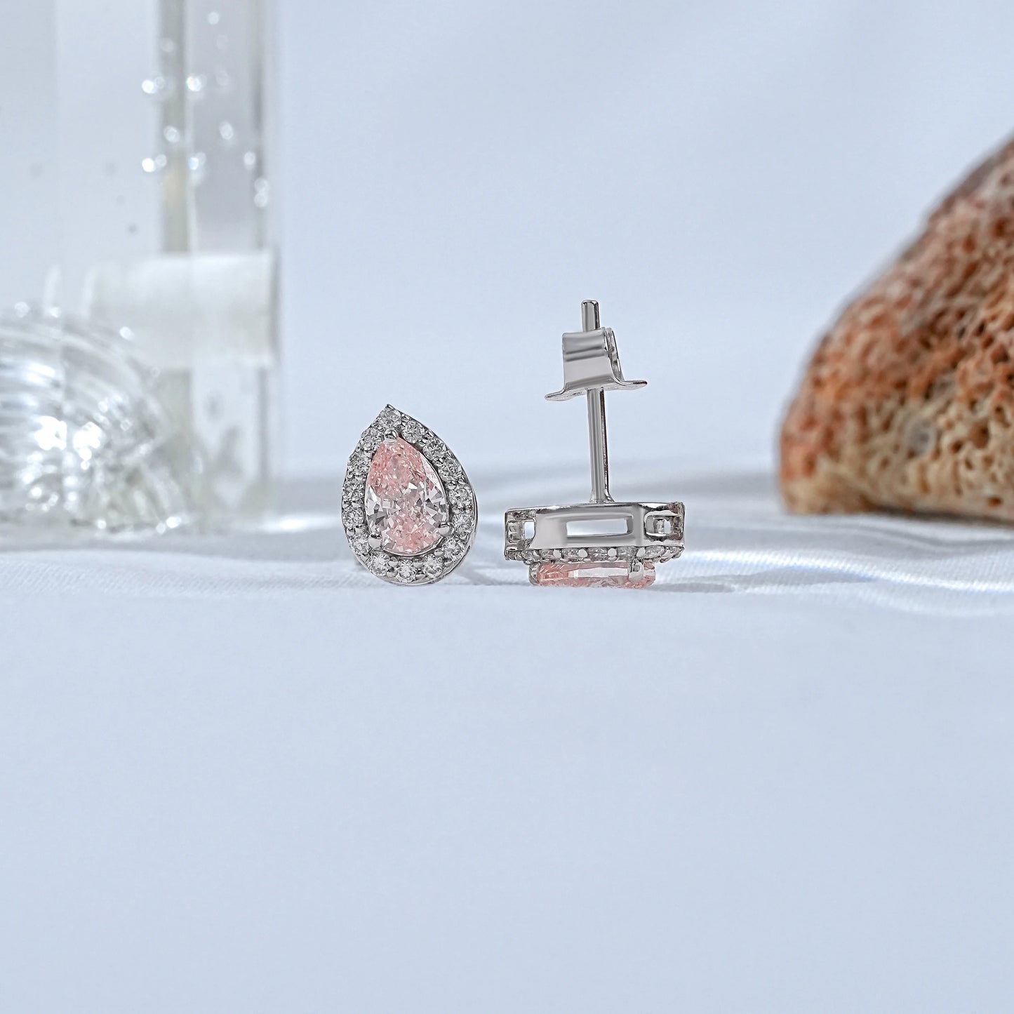 Pink diamond teardrop stud earrings secure prong setting front and back view showing white gold butterfly clasp post detail soft background