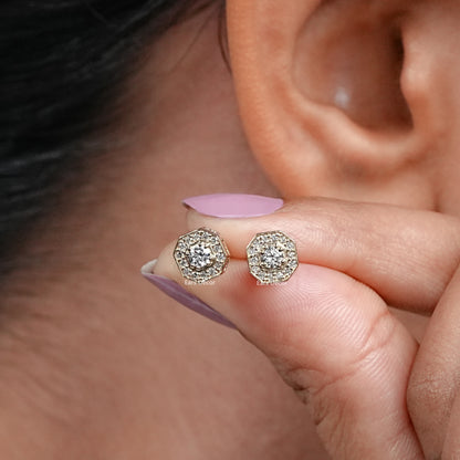 bezel set brilliant cut octagon shaped diamond stud earring held between thumb and finger