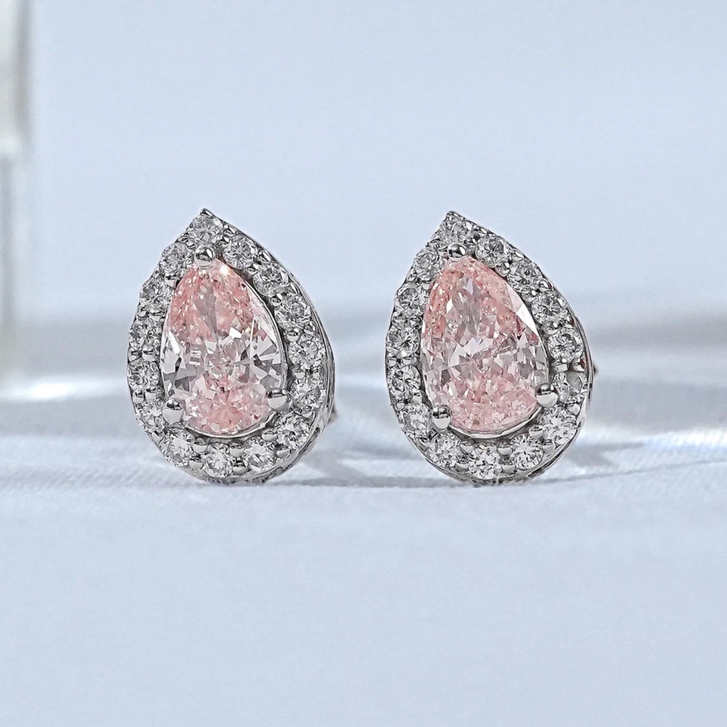 Pear shaped pink diamond stud earrings with double halo white diamond setting white gold matching pair close-up product shot