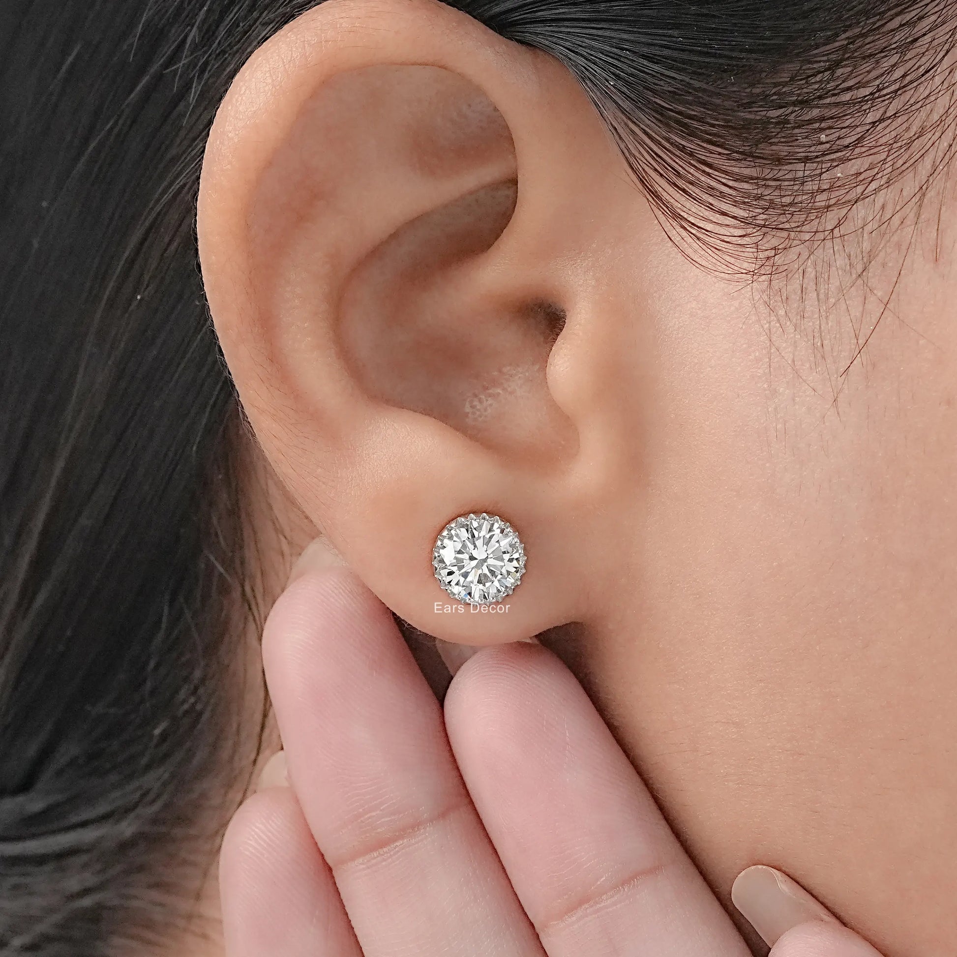 Screw back moissanite stud earrings secure fit white gold worn on model ear hand pose close-up