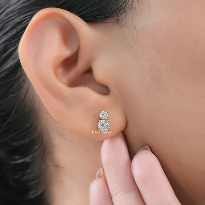 Dainty toi et moi diamond earrings two round stones women yellow gold worn on model ear close-up dark hair warm skin nude nails fingers touching